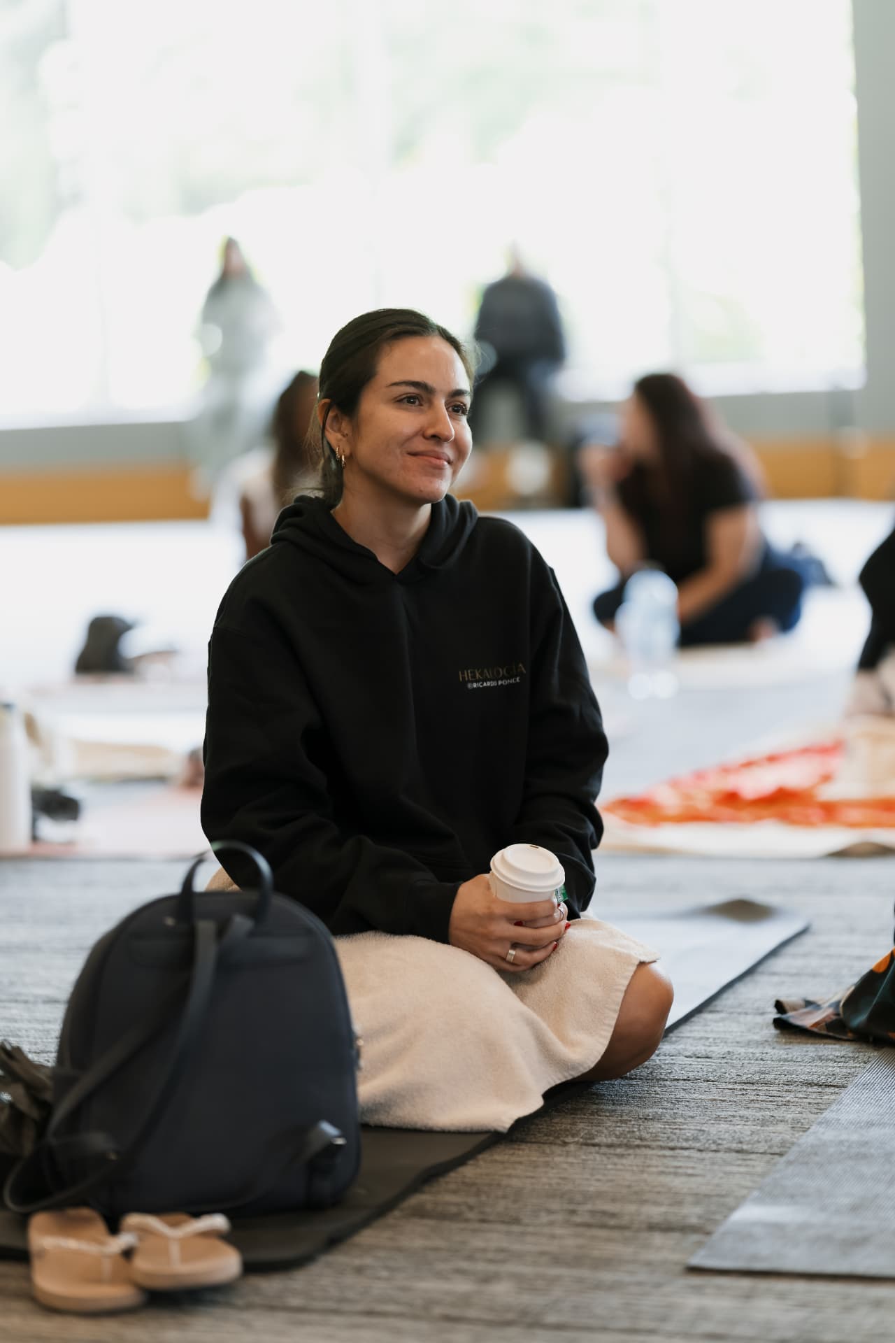 Participante sonriente sentada con un café durante una pausa.