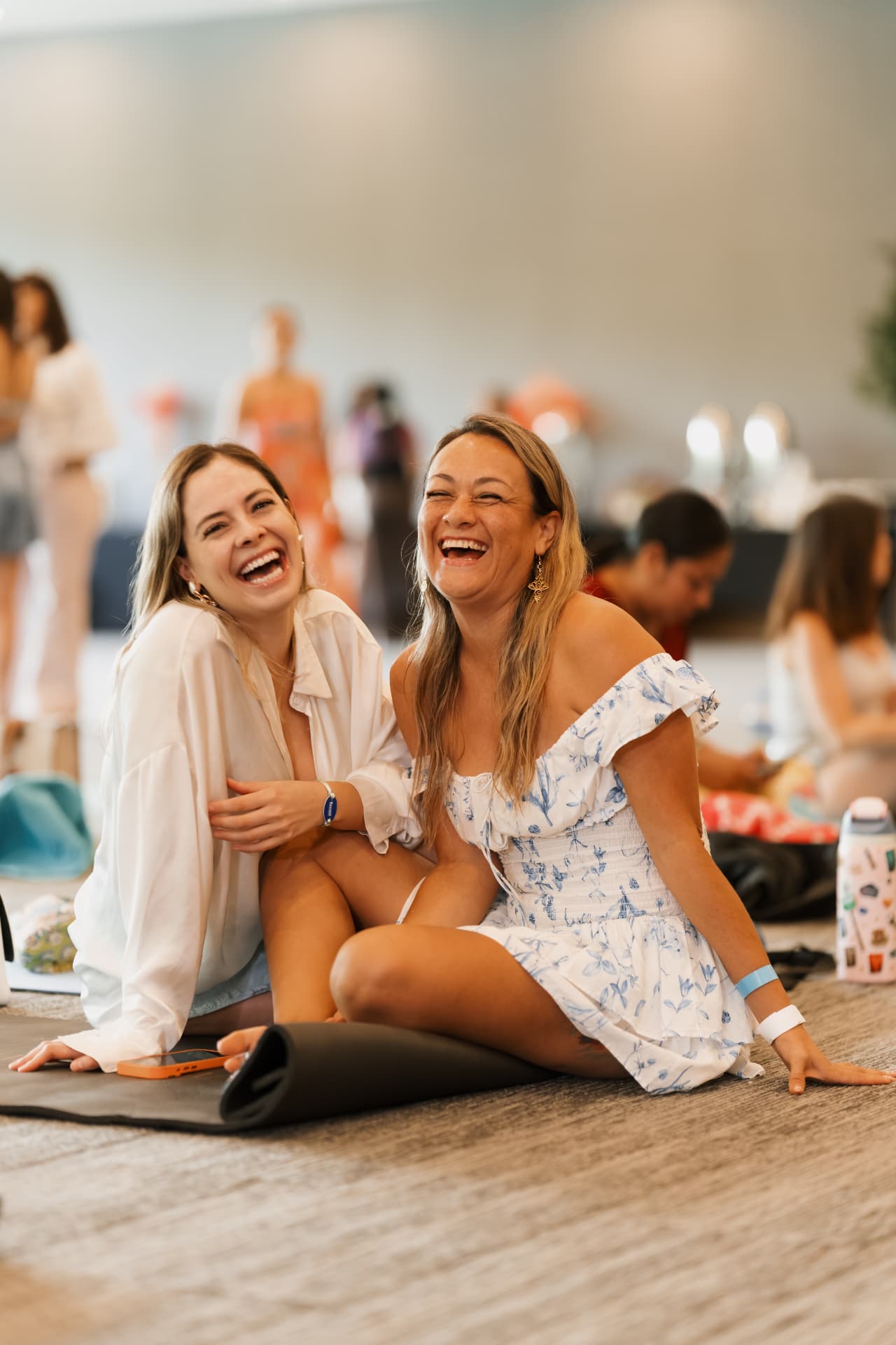 Dos participantes ríen sentadas sobre sus tapetes.