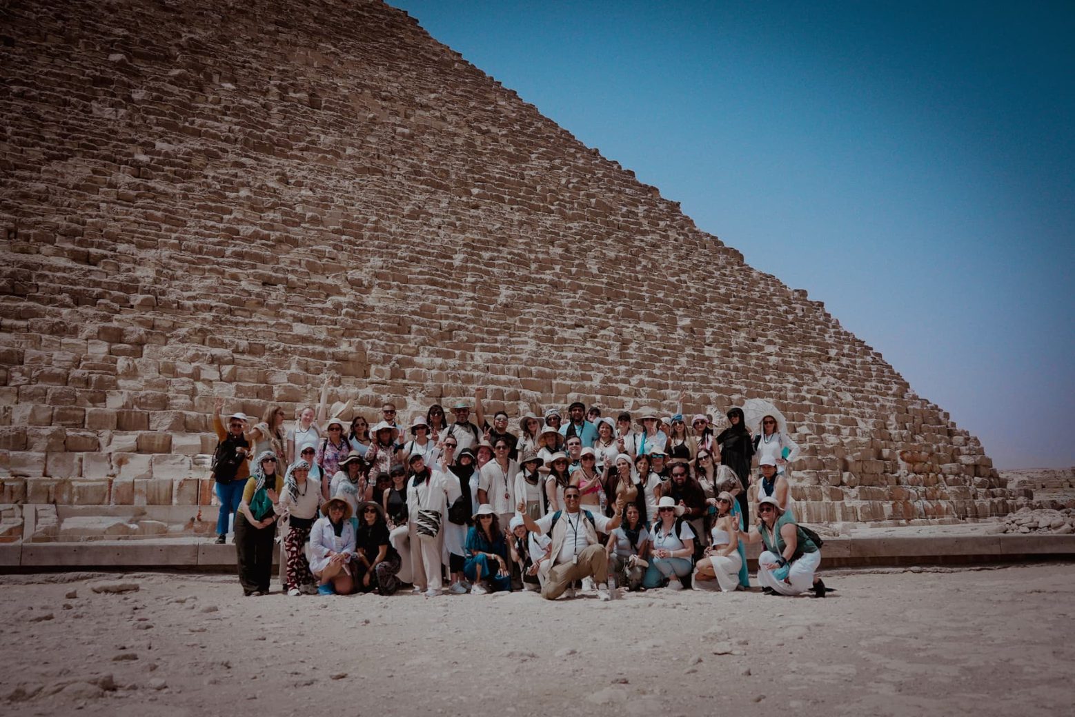 Fotografía grupal de todos los participantes al pie de la Gran Pirámide de Guiza.